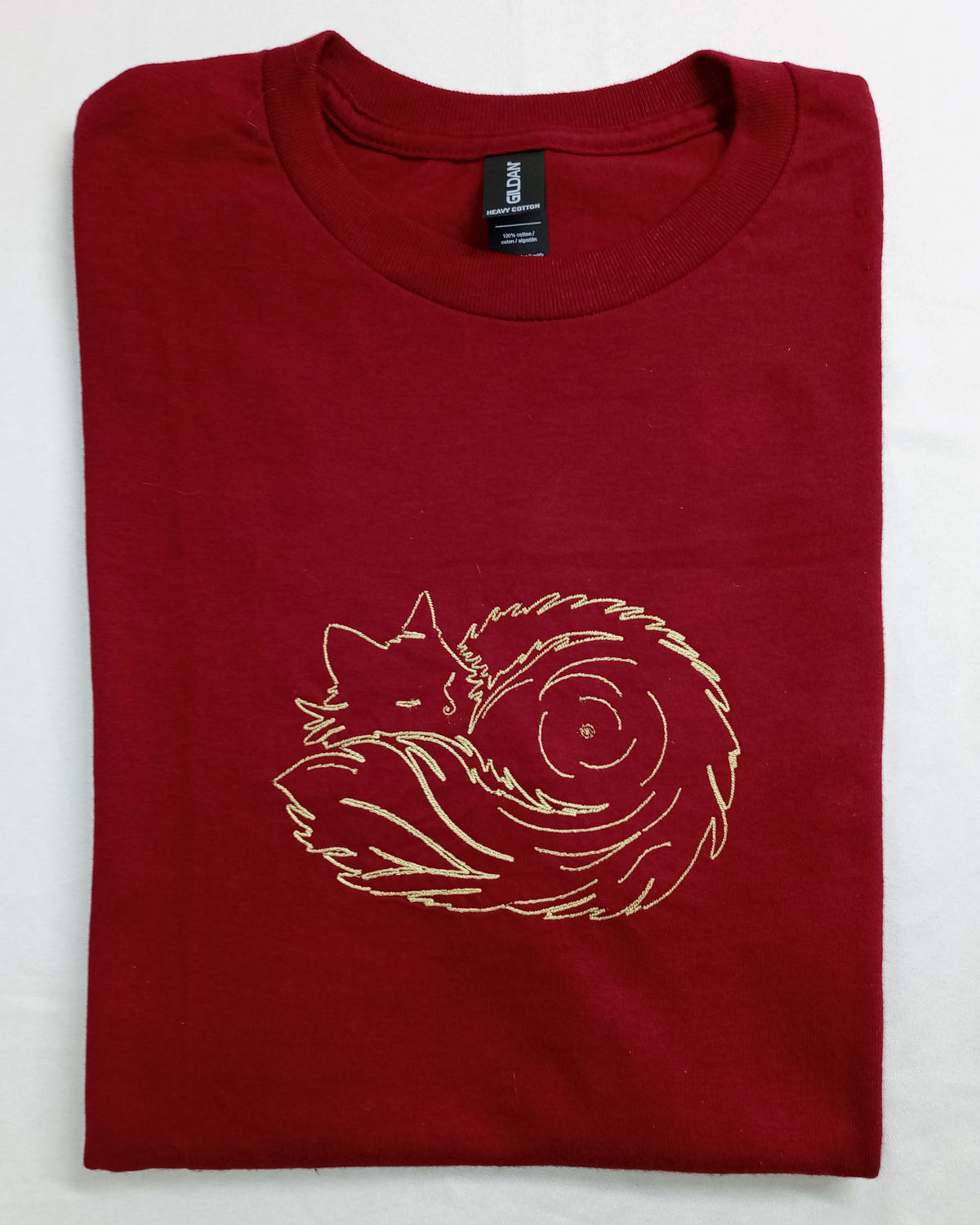 Pelote de poils - Fil doré brillant sur t-shirt rouge
