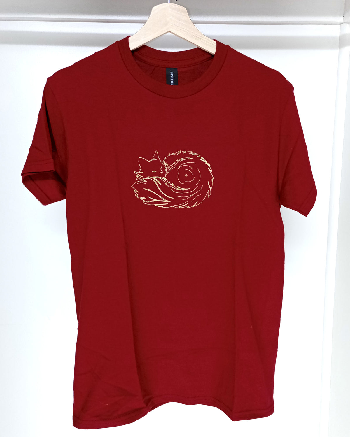 Pelote de poils - Fil doré brillant sur t-shirt rouge