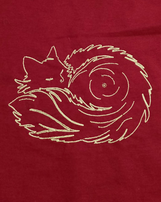 Pelote de poils - Fil doré brillant sur t-shirt rouge